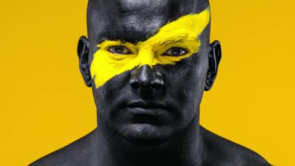 Closeup portrait of man bodybuilder athlete with yellow color on face art  and black body paint. Colorful photo of the guy with bodyart. Stock Video  Footage by ©MikeOrlov #348842196